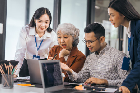 Four asian people in an office, working together on laptops, discussing tasks. annual gathering where attendees share and discuss opinions, presentation teamwork group meeting laptop in boardroomの写真素材