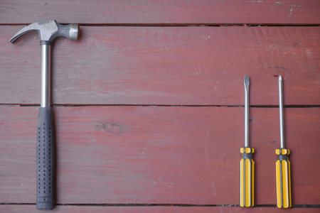 assortment of well-used hand tools spread out on a worn wooden surface, indicative of a workspace or...
