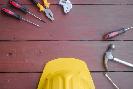 assortment of well-used hand tools spread out on a worn wooden surface, indicative of a workspace or a workbench.の写真素材