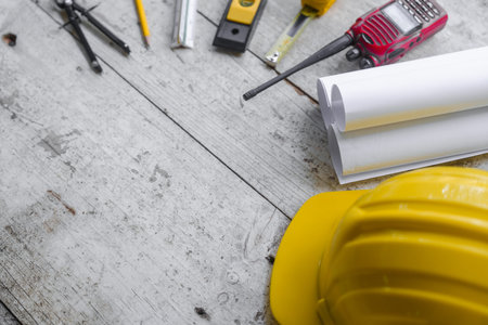 Top view construction tools such as a yellow hard hat, spirit level, measuring tape, folding ruler...