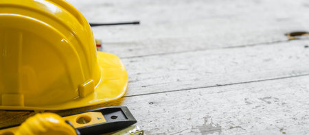 yellow safety helmet and rolled up architectural blueprints on a wooden desk, indicative of an architect's work area, possibly at a construction site.の写真素材