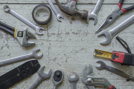 assortment of well-used hand tools spread out on a worn wooden surface, indicative of a workspace or...