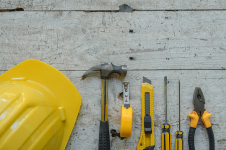 assortment of well-used hand tools spread out on a worn wooden surface, indicative of a workspace or a workbench.の写真素材