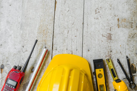Top view construction tools such as a yellow hard hat, spirit level, measuring tape, folding ruler...