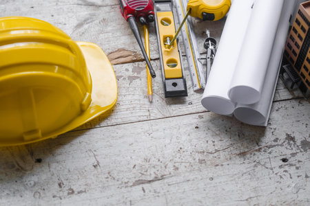 Top view construction tools such as a yellow hard hat, spirit level, measuring tape, folding ruler...