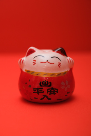 Neko or a lucky charm cat with traditional chinese character that means ' Prosperity within and outside of the house' . This neko was shot on a plain isolated red background.の写真素材