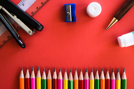 Stationaries such as colorful pensil, ruler, stapler, sharpener, pen amd glue shot on a plain isolated red background as wallpaper.の写真素材