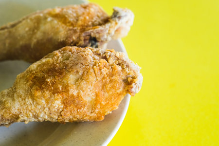 Fried Drumstick chicken shot macro on an isolated yellow background.の写真素材