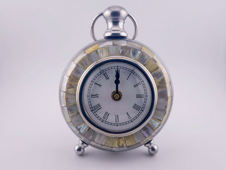 Vintage clock with pearl inlays set at 12 o'clock. The shot is taken on a white back ground.