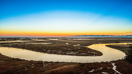 A river winding through the marsh as the sunrises over the horizon.