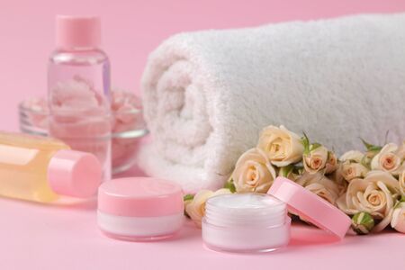 cosmetics for face and body in pink bottles with fresh roses on a delicate pink background. cream and lotion. spa.の写真素材