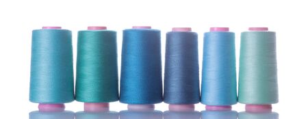A bobbin with threads in blue tones on a white isolated background. accessories for sewingの写真素材