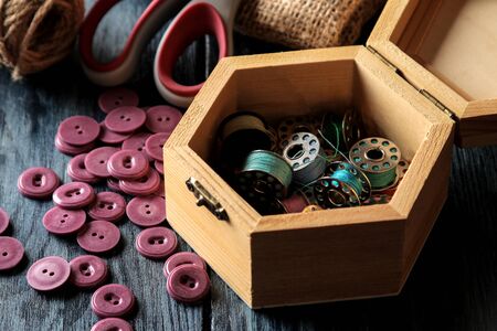 Accessories for sewing and needlework. casket with bobbins close-up on a dark blue wooden backgroundの写真素材