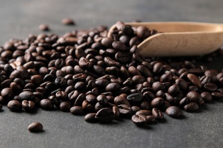 Fried coffee beans close-up and wooden spoon on a black backgroundの写真素材