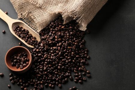 Fried coffee beans wooden spoon and bowl on a black background. top viewの写真素材