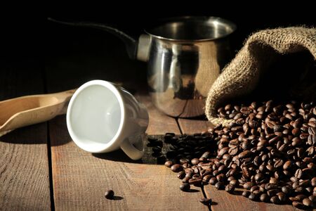 Composition with coffee beans and a cup and cezve on a brown wooden tableの写真素材