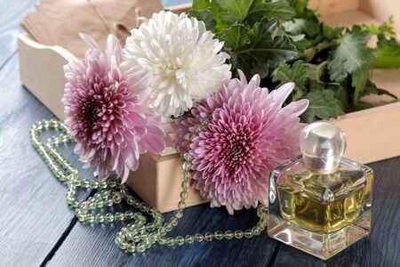 Autumn chrysanthemum flowers with beads and spirits on a dark blue tableの写真素材