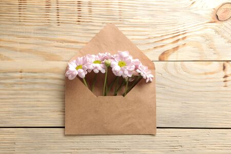 Autumn chrysanthemum flowers in an envelope on a natural wooden table. top viewの写真素材