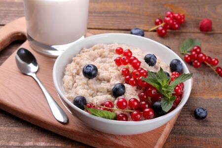 Oatmeal with berries and milk in a bowl on a brown wooden table. breakfast. healthy food.の写真素材