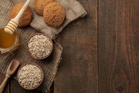 Dry oatmeal, honey and oatmeal cookies. food. healthy food. on a brown wooden table. top view with space for inscriptionの写真素材