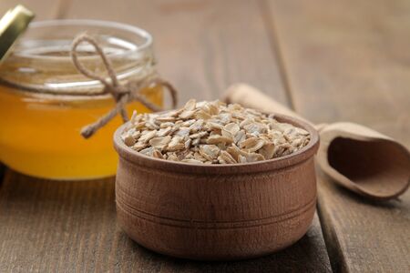 Dry oatmeal in a wooden bowl and honey. food. healthy food. on a brown wooden table.の写真素材