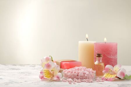 Spa composition with sea salt, aroma oils and handmade soap with flowers. spa concept. on a light background. with space for inscriptionの写真素材