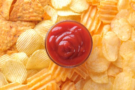 Background from different chips and red sauce closeup. Snacks. unhealthy food.の写真素材