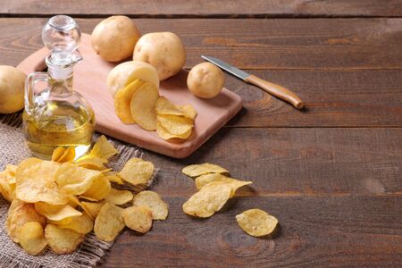 Chips with butter and fresh potatoes on a brown wooden table. ingredientsの写真素材