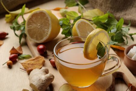 Autumn composition with hot tea with ginger and lemon on a natural wooden table.の写真素材
