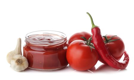 Red sauce in a jar and fresh ingredients, tomatoes, peppers and garlic on a white isolated background. Tomato sauce. Ketchupの写真素材