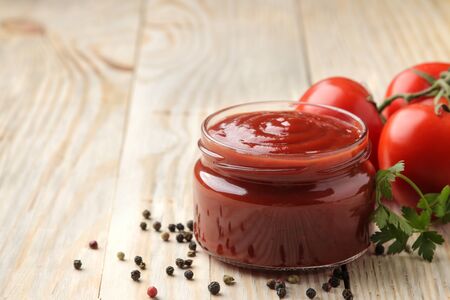 Red sauce in a jar closeup with fresh tomatoes on a natural wooden table. with space for inscriptionの写真素材