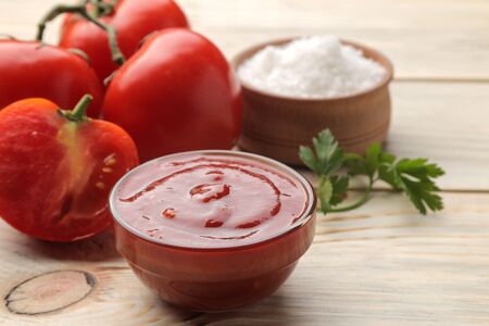 Red sauce in a bowl closeup with fresh tomatoes on a natural wooden table.の写真素材
