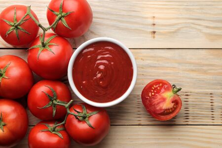Red sauce in a bowl with fresh ingredients, tomatoes on a natural wooden table. view from aboveの写真素材