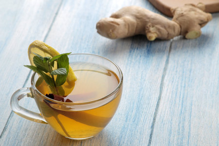 Composition with green hot tea with cinnamon, lemon and ginger on a blue wooden background