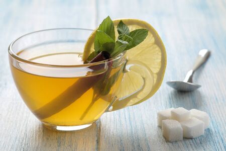 Composition with green hot tea with cinnamon, lemon on a blue wooden backgroundの写真素材