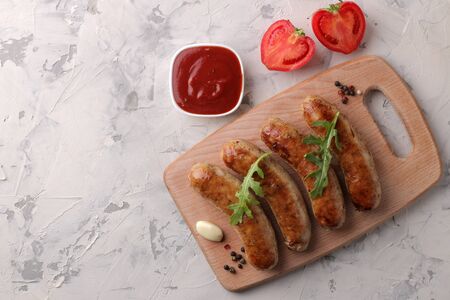 Grilled sausages with a variety of vegetables tomatoes and garlic, red sauce and spices on a light background. top viewの写真素材