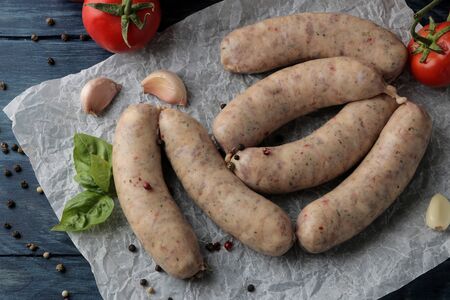 Raw sausages with ingredients for cooking tomatoes, garlic, butter and basil. on a blue wooden table. View from aboveの写真素材