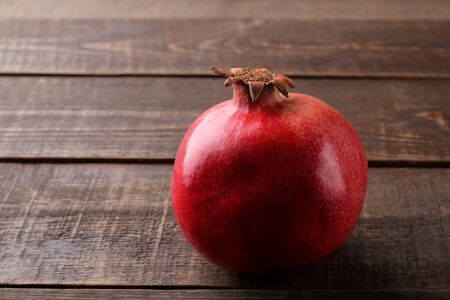 Large ripe red pomegranate fruit on a brown wooden table with space for inscription.の写真素材