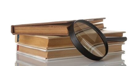 Pile of books and a magnifier on a white isolated background. Old books. Education. school. studyの写真素材