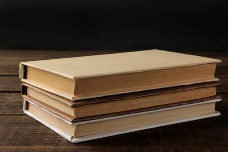 A stack of books on a brown wooden table and on a black background. Old books. Education. school. studyの写真素材