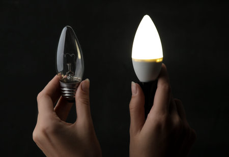 The concept of saving electricity. Light bulbs in hands on a black background. the choice between a...