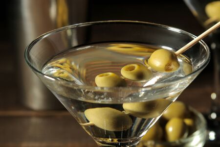 Martini in a glass wineglass with green olives on a skewer on a brown wooden table. cocktails. barの写真素材