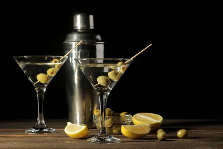 Martini in a glass wineglass with green olives on a skewer on a brown wooden table. cocktails. barの写真素材