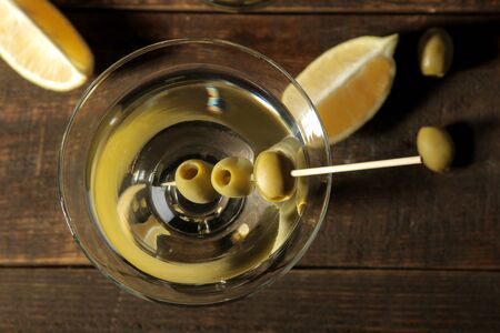 Martini in a glass wineglass with green olives on a skewer on a brown wooden table. cocktails. barの写真素材