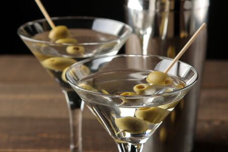 Martini in a glass wineglass with green olives on a skewer on a brown wooden table. cocktails. barの写真素材