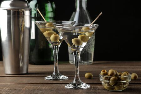 Martini in a glass wineglass with green olives on a skewer on a brown wooden table. cocktails. barの写真素材