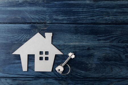 The concept of buying a home. Decorative hut and house keys on a blue wooden background with a place for an inscription. top viewの写真素材