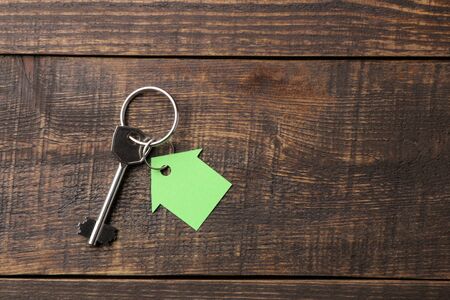 The concept of buying a home. Keys with keychain house on a brown wooden background. view from above. with space for inscriptionの写真素材