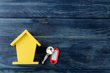The concept of buying a home. Decorative hut and house keys on a blue wooden background with a place for an inscription. top viewの写真素材
