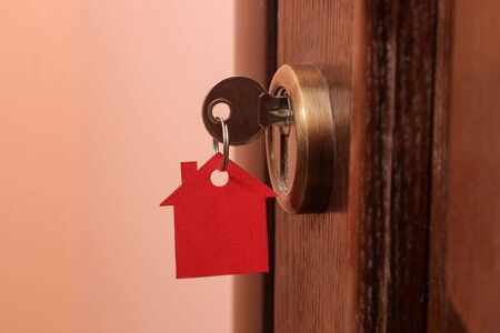 The concept of buying a home. Keys with keychain house in the door lock close-upの写真素材